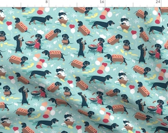 May include: A teal blue fabric with a repeating pattern of black dachshund dogs. The dogs are in various poses, including eating hot dogs, grilling, and taking a bath. There are also red hearts, yellow balloons, and white clouds in the pattern.
