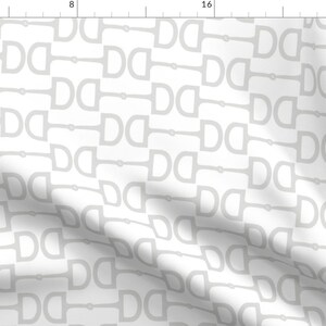 May include: A white fabric with a repeating pattern of gray stirrups. The stirrups are arranged in a diagonal pattern.