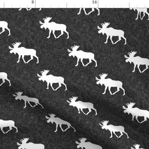 May include: A black and white fabric with a repeating pattern of white moose silhouettes. The fabric has a textured, linen-like appearance.