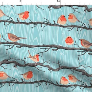 May include: A seamless pattern featuring red robins perched on bare branches against a blue woodgrain background.