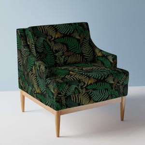 May include: A green and gold armchair with a fern pattern upholstery. The chair has a dark wood frame and legs.
