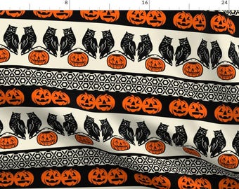 May include: A black and white fabric pattern with alternating rows of orange jack-o'-lanterns and black owls. The pattern is repeated on a cream background.