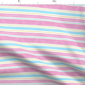 May include: Pink, blue, and yellow striped fabric with a subtle watercolor effect. The fabric is folded and has a soft, textured look.