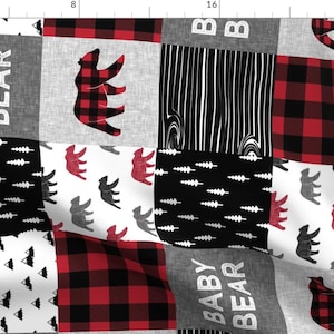 May include: A patchwork fabric featuring a red and black buffalo plaid pattern, a black and white woodgrain pattern, a black and white pattern of small trees, a black and white pattern of small triangles, and a gray and white pattern with the text "BABY BEAR". The fabric also features a red and black plaid bear, a gray bear, and a red bear.