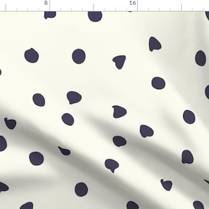 May include: A white fabric with a repeating pattern of dark blue irregular circles. The fabric has a subtle texture and a slightly wrinkled appearance.