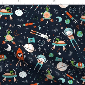 Op de afbeelding: Een donkerblauwe stof met een herhalend patroon van ruimtethema-illustraties. Het patroon bevat sterren, planeten, raketten, schildpadden, katten en aliens. De illustraties zijn in verschillende kleuren, waaronder oranje, blauw, groen en wit.