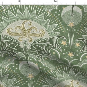 Puede incluir: Una tela estampada en verde y dorado con un diseño repetido de un dragón con las alas extendidas, estrellas y un sol radiante. La tela tiene un aspecto vintage e ilustrado.