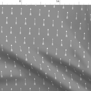 May include: A grey fabric with a repeating pattern of white arrows pointing upwards. The arrows are simple and minimalist, creating a subtle and modern design.