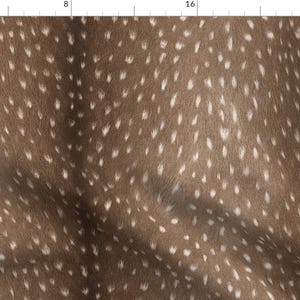 以下が含まれることがあります： 茶色と白の斑点模様の生地のクローズアップ。生地は柔らかく、ふわふわとした質感で、動物の毛皮を連想させる。