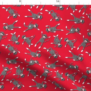 May include: A red fabric with a repeating pattern of gray sock monkeys. The monkeys are in various poses with their arms and legs outstretched.