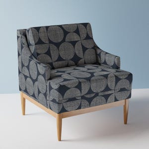 May include: A navy blue armchair with a geometric pattern of circles and semi-circles. The chair has a wooden frame and legs.