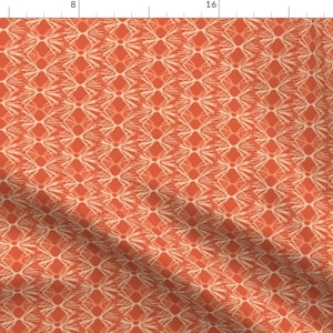 May include: A repeating pattern of orange and cream geometric shapes. The pattern is made up of diamonds and swirls. The background is orange and the shapes are cream.