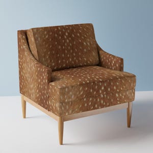 May include: A brown armchair with a spotted upholstery pattern. The chair has a high back and a wide seat. The chair is made of wood and has four legs.