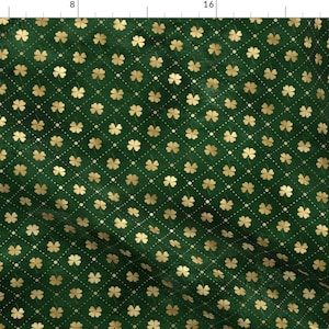 以下が含まれることがあります： 緑色の生地に、金色の四つ葉のクローバーが繰り返しパターンで描かれています。クローバーはダイヤモンド型に配置されています。