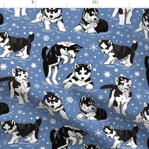 Puede incluir: Un patrón sin costuras con cachorros husky negros y blancos sobre un fondo azul con copos de nieve blancos. Los cachorros están en varias poses, incluyendo sentados, de pie y jugando.