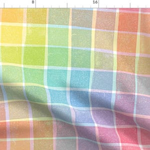 May include: A rainbow plaid fabric with a textured, slightly faded look. The fabric is folded diagonally, showing the different colors of the plaid pattern.