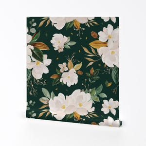 Op de afbeelding: Een naadloos patroon met witte magnolia bloemen met een aquareleffect op een donkergroene achtergrond. De bloemen worden omringd door groene bladeren en bruine stengels.