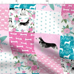 May include: A patchwork fabric design featuring a variety of patterns, including pink and white floral designs, paw prints, bones, and a silhouette of a husky dog. The fabric is perfect for quilting, crafting, and other sewing projects.