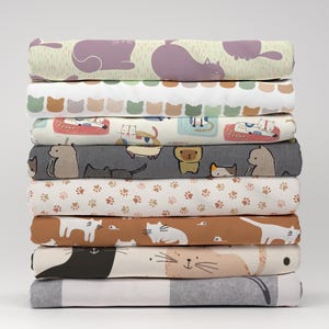 Peut inclure: Un ensemble de 10 échantillons de tissus différents présentant divers motifs de chats. Les tissus sont de différentes couleurs, notamment le vert, le violet, le marron, le gris et le blanc. Les motifs comprennent des chats dormant, jouant et se prélassant.