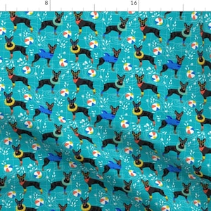 May include: A teal blue fabric with a repeating pattern of black dogs wearing leis and sunglasses. The dogs are holding beach balls and are surrounded by green leaves.