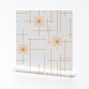 Op de afbeelding: Witte behang met een herhalend patroon van oranje geometrische vormen en sterren.