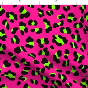 May include: A pink fabric with a black and green leopard print pattern.