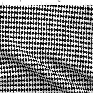 May include: Black and white diamond pattern fabric. The repeating design features a grid of black diamonds on a white background. The fabric is folded, creating shadows and depth.