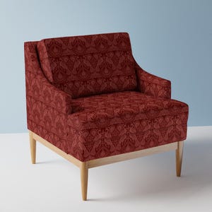 May include: A red armchair with a patterned fabric featuring a repeating design of stylized birds. The chair has a wooden frame with four legs.