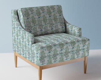 Puede incluir: Un sillón azul claro con un patrón floral con árboles y pájaros. El sillón tiene un marco y patas de madera.