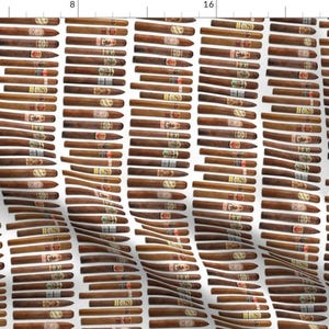 May include: A white background with a repeating pattern of brown cigars. The cigars are arranged in rows and columns, and they are all the same size and shape.
