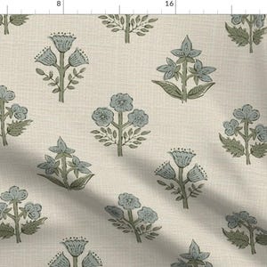 Könnte beinhalten: Ein Textilstoff mit einem sich wiederholenden Blockdruckmuster aus kleinen Blumenmotiven in gedämpftem Blau und Salbeigrün auf hellbeigem Hintergrund. Das Design zeigt verschiedene Blumenformen mit sichtbaren Stängeln und Blättern auf einer Webstruktur.