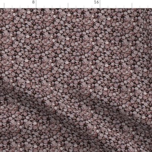 May include: A seamless pattern of hundreds of small, round, pink and white skulls. The skulls are arranged in a random pattern and create a textured, almost grainy effect.