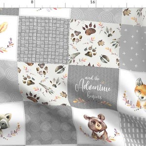 May include: A grey and white patchwork fabric with a woodland animal theme. The fabric features a deer, fox, raccoon, and bear, along with paw prints, leaves, and the text "and the Adventure begins".