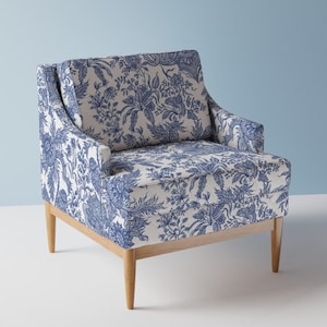 May include: A blue and white floral patterned armchair with wooden legs. The chair has a high back and a wide seat.