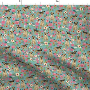 May include: A seamless pattern featuring a light blue background with a repeating design of brown and tan Border Terriers standing in a field of pink, white, and green flowers.