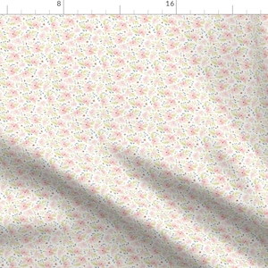 May include: A fabric with a delicate floral pattern. The design features small pink flowers, tiny blue dots, and light green leaves scattered across a white background. The overall effect is soft and feminine, suitable for various craft projects.