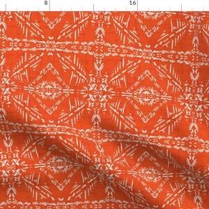 May include: Orange fabric with a white geometric pattern. The pattern is made up of repeating diamonds and triangles.