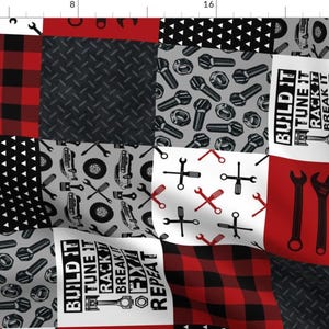 May include: A red and black plaid fabric with a patchwork design. The fabric features different patterns, including a black and white checkered pattern, a gray pattern with wrenches and nuts, and a white pattern with red wrenches and screwdrivers. The fabric also includes the text "BUILD IT TUNE IT RACK IT BREAK IT FIX IT REPEAT".