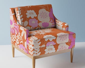 May include: A mid-century modern armchair upholstered in a vibrant orange fabric with a large-scale floral pattern in shades of pink and white. The chair has a wooden frame and legs.