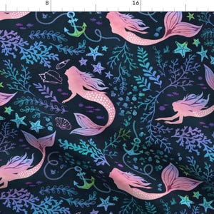 May include: Dark navy fabric featuring a repeating pattern of pink mermaids with flowing hair and tails. The design includes teal and purple coral, starfish, seashells, and anchors, creating an underwater theme.