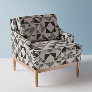 May include: A black and white geometric patterned armchair with wooden legs. The chair has a square back and a wide seat.