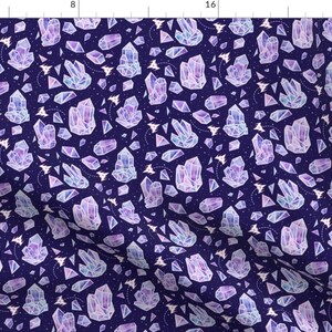 Pode incluir: Um padrão sem costura que apresenta um design repetitivo de cristais roxos e azuis sobre um fundo azul escuro. Os cristais são delineados em branco e têm um efeito aquarela. Pequenas estrelas brancas estão dispersas por todo o padrão.