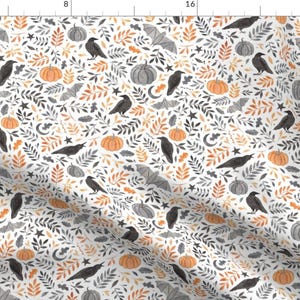 May include: White fabric with a repeating pattern of pumpkins, crows, bats, leaves, stars, and crescent moons. The pumpkins are orange and gray, the crows are black, and the leaves are in shades of orange and gray.