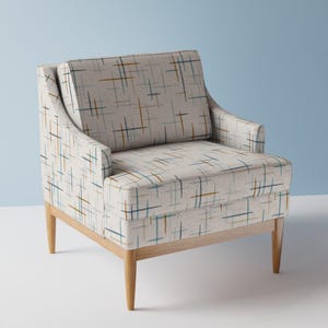 May include: A white armchair with a geometric pattern in shades of blue and brown. The chair has a wooden frame and legs.