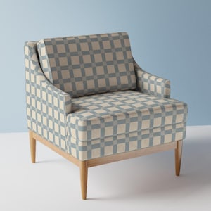 May include: A contemporary armchair with a light wood frame and legs. The chair has a blue and cream checkered pattern on the seat, back, and arms. The background is a solid light blue.