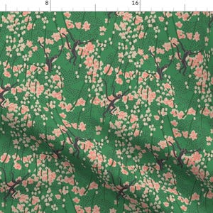 Könnte beinhalten: Ein grüner Stoff mit einem sich wiederholenden Muster aus rosa Blüten und schwarzen Affen, die auf Ästen klettern. Der Hintergrund ist dunkelgrün mit einem dezenten weißen Punktmuster.