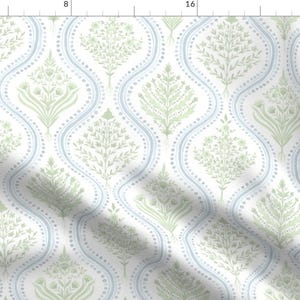 May include: A white fabric with a repeating pattern of light blue and green stylised floral designs. The pattern features a series of curved lines and dots.