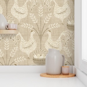 May include: Wallpaper featuring a repeating pattern of cream-coloured roosters, wheat stalks, and baskets of eggs on a textured beige background. A light grey ceramic pitcher and a small matching cup sit on a wooden coaster in the foreground.