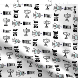 May include: White fabric with a repeating pattern of cartoon robots, trophies, and other mechanical shapes in shades of gray and black. The robots have light blue screens. The design is whimsical and playful.
