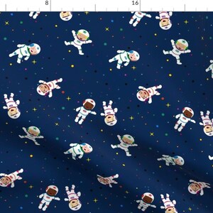 Puede incluir: Una tela azul marino con un patrón repetido de astronautas en trajes espaciales blancos con acentos coloridos. Los astronautas flotan en un espacio azul oscuro con estrellas blancas.